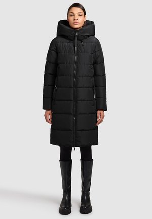 Czarna pikowana kurtka puchowa z kapturem, zamkiem na przodzie i pikowanym wzorem. Kurtka sięga kolan, ma boczne kieszenie i jest zestawiona z czarnymi wysokimi kozakami do kolan.
