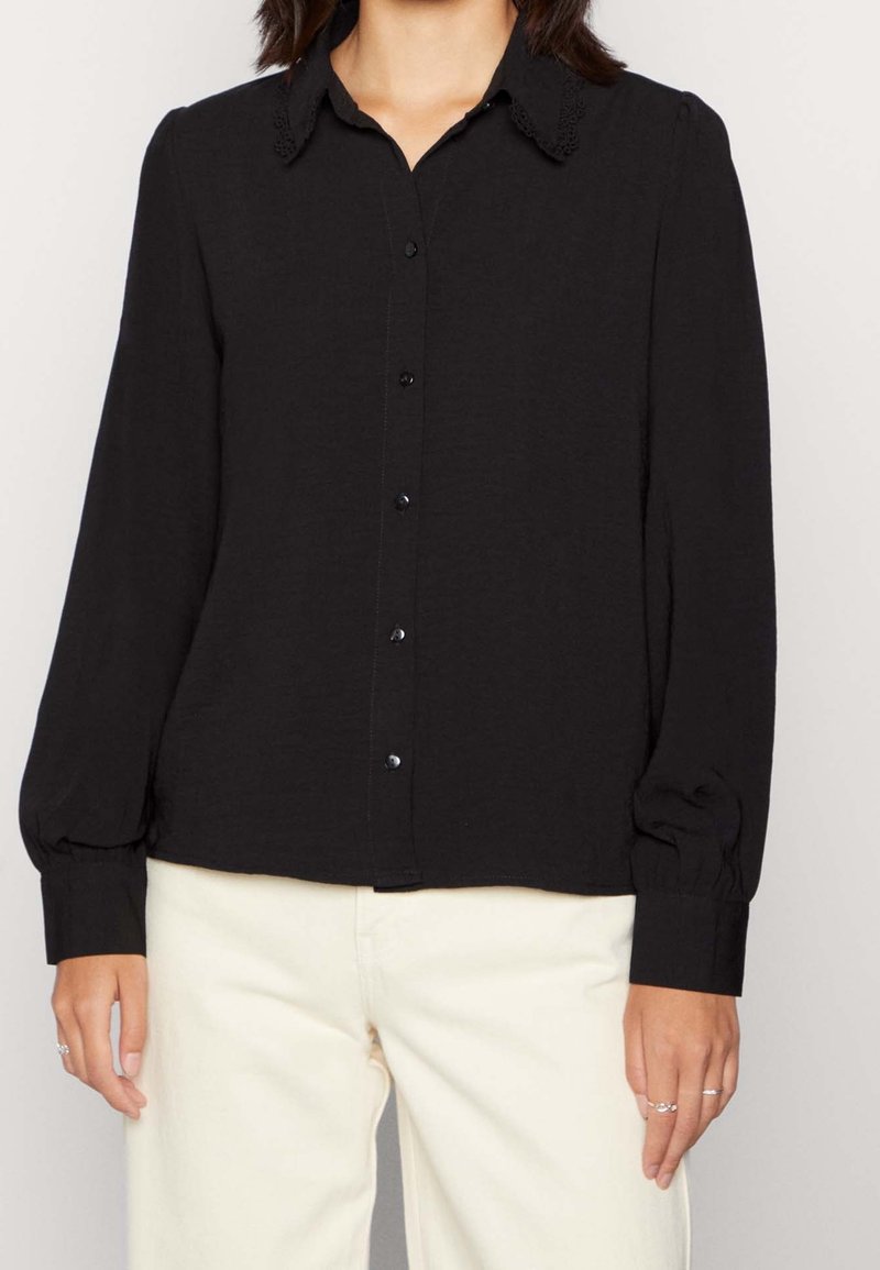 Black button-up shirt with a lace-detailed collar, long sleeves with elastic cuffs, and a textured fabric design.