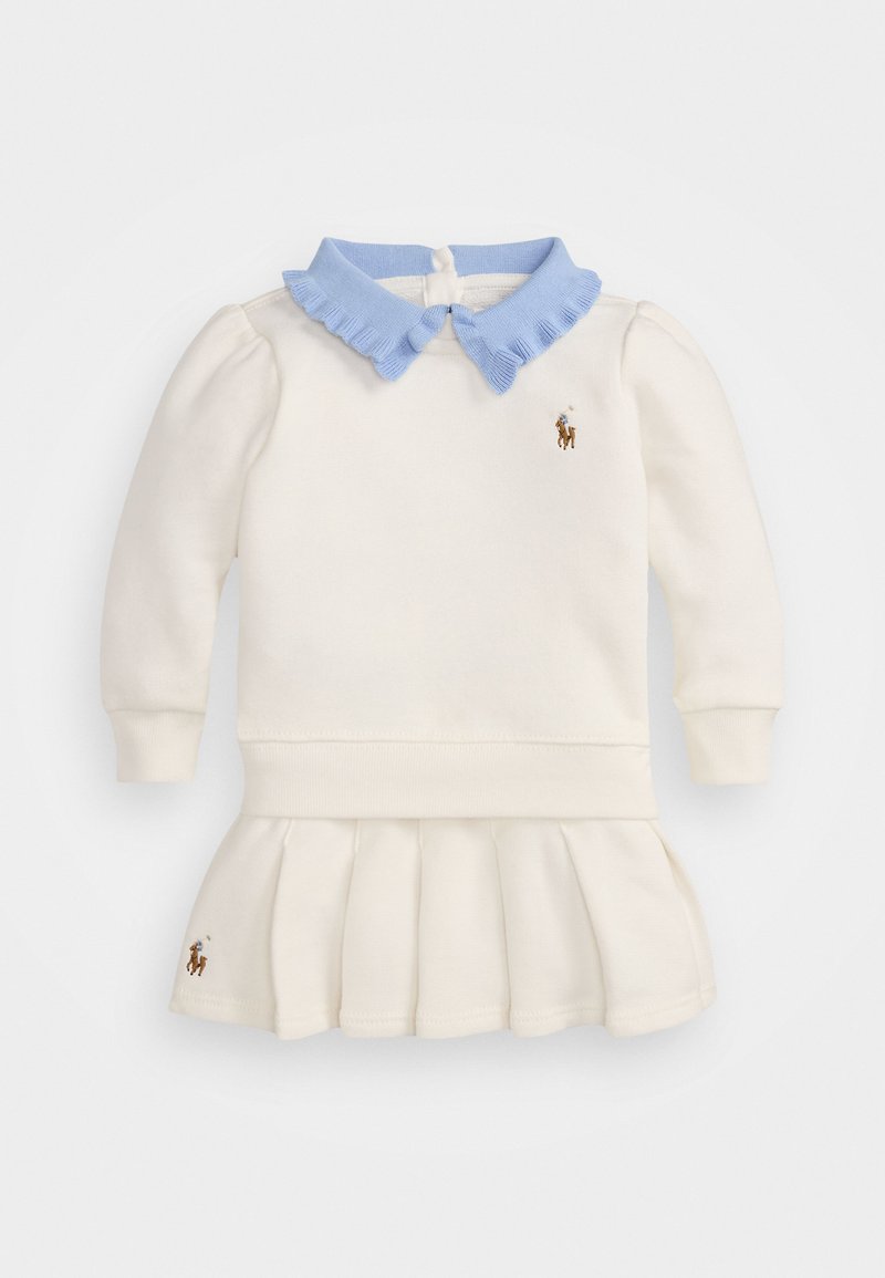 Cream colored dress with long sleeves, a light blue ruffled collar, and pleated skirt. Features embroidered logo on chest and hem.