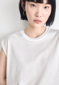 White, short-sleeve t-shirt with a classic round neckline, made from a lightweight fabric. Features a relaxed fit and soft texture.