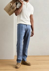 Crème geribbelde polo met korte mouwen, lichtblauwe linnen broek, beige suède loafers en een tan tas met bruine accenten. Minimalistisch ontwerp.