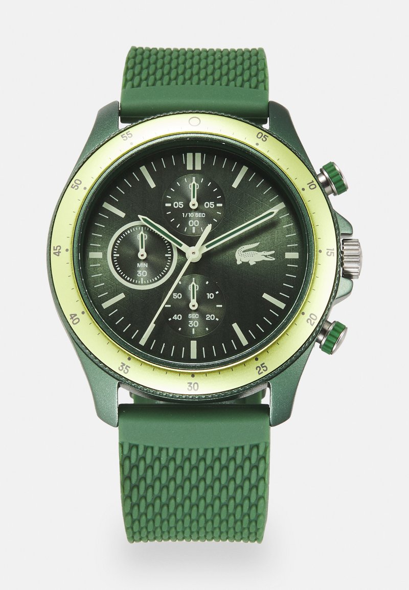 Montre avec bracelet en caoutchouc vert et cadran vert foncé, comportant trois sous-cadrans, une lunette jaune et une quincaillerie argentée. Logo Lacoste sur le cadran.