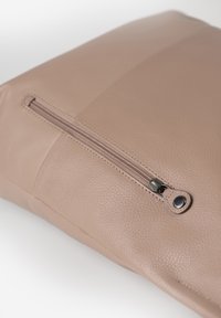 Borsa in pelle marrone con finitura testurizzata, dotata di una tasca frontale con zip e un accento in metallo circolare vicino alla cerniera. Aspetto morbido e liscio.