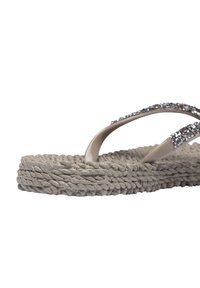 Sandalo infradito beige con suola a trama intrecciata, caratterizzato da due cinturini eleganti decorati con strass trasparenti per un tocco in più.