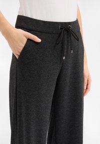 Dunkelgraue Jogginghose aus weichem Stoff mit elastischem Bund, Kordelzug und seitlichen Taschen.