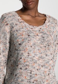 Texturierter Strickpullover in Grau mit orangefarbenen und braunen Sprenkeln, mit einem weiten Rundhalsausschnitt und langen Ärmeln. Weicher, kuscheliger Stoff.