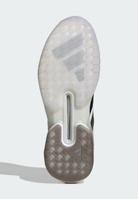 Podeszwa buta z teksturowanym, przezroczystym wzorem; zawiera okrągłe uchwyty, centralną rowek oraz czarno-białą grafikę z detalem logo.