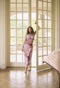 Lihtne, ilma varrukateta roosa kleit, millel on abstraktne marmoreerimis muster; sile kangas; keskpikkuses, liibuv siluett; kantud kergete sandaalidega.