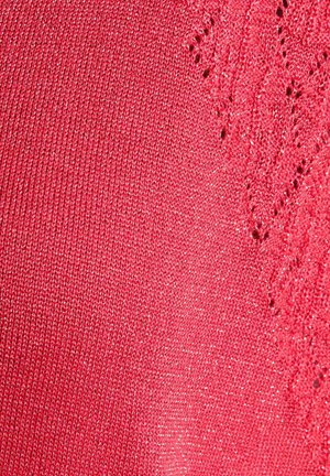 Tessuto rosso lavorato a maglia con sottili fili glitterati e motivo in pizzo sul lato destro, che mostra la trama e i dettagli intricati.