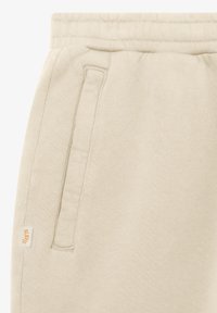 Beżowe spodnie dresowe z elastycznym pasem, boczną kieszenią i małą metką z tkaniny na lewym szwie bocznym.