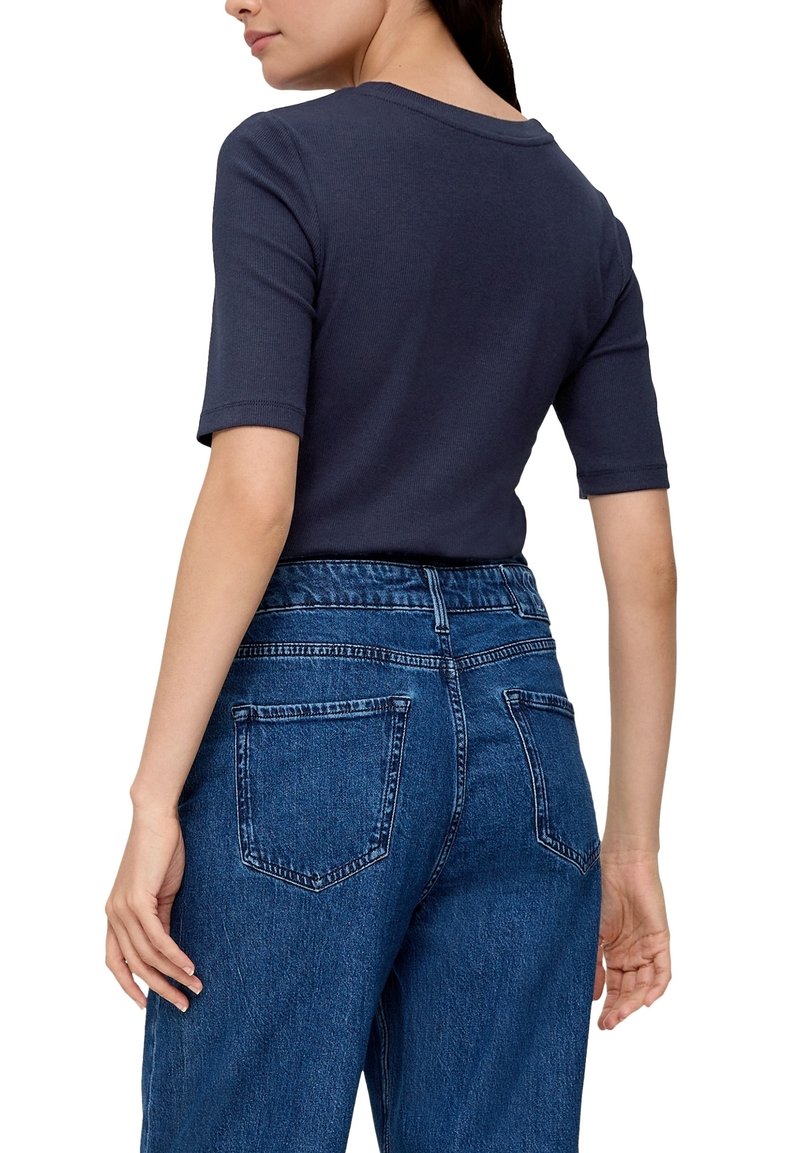 Granatowa, prążkowana koszulka z krótkim rękawem, dopasowany krój, połączona z niebieskimi dżinsami z wysokim stanem, posiadającymi tylne kieszenie i wyblakłą teksturę.