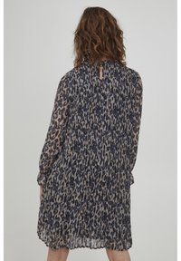 Genomskinlig djurmönstrad klänning med långa ärmar, plisserad textur och nyckelhålsöppning i ryggen. Huvudfärger: beige, blå och svart.