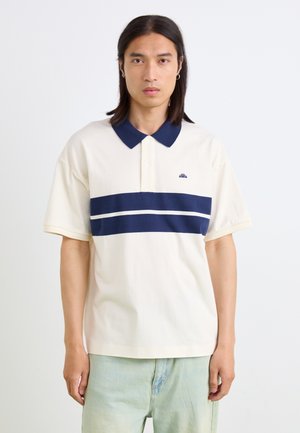 Cremefarbendes Baumwoll-Polohemd mit navyfarbenem Kragen, ausgestattet mit zwei horizontalen navyblauen Streifen und einem kleinen Logo auf der Brust. Kurze Ärmel.