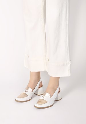White slingback shoes with a shiny gold accent and triangular cutouts, featuring a chunky white block heel and smooth texture.