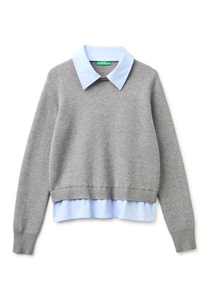 Maglione grigio lavorato a maglia indossato sopra una camicia celeste con colletto e orlo visibili, su sfondo bianco.