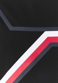 Sort stof med geometriske mønstre i mørkegrå, rød og hvid. Glat tekstur med en let glans på de farvede accenter.