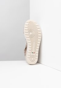 Beige podrážka boty s texturovaným vzorem, obsahující kruhový design a branding. Číslo 37 a "Vyrobeno v Itálii" vyraženo na boku.