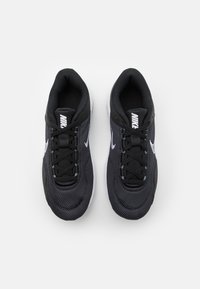 Crne mrežaste Nike tenisice s sivim detaljima, okrugli nožni deo, podstavljeni ovratnik i beli gumeni đon. Imaju klasično vezivanje i logo na jeziku.
