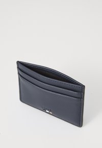 Navy leather cardholder featuring four slots, clean lines, and subtle embossed logo detailing. Smooth texture with black interior.
