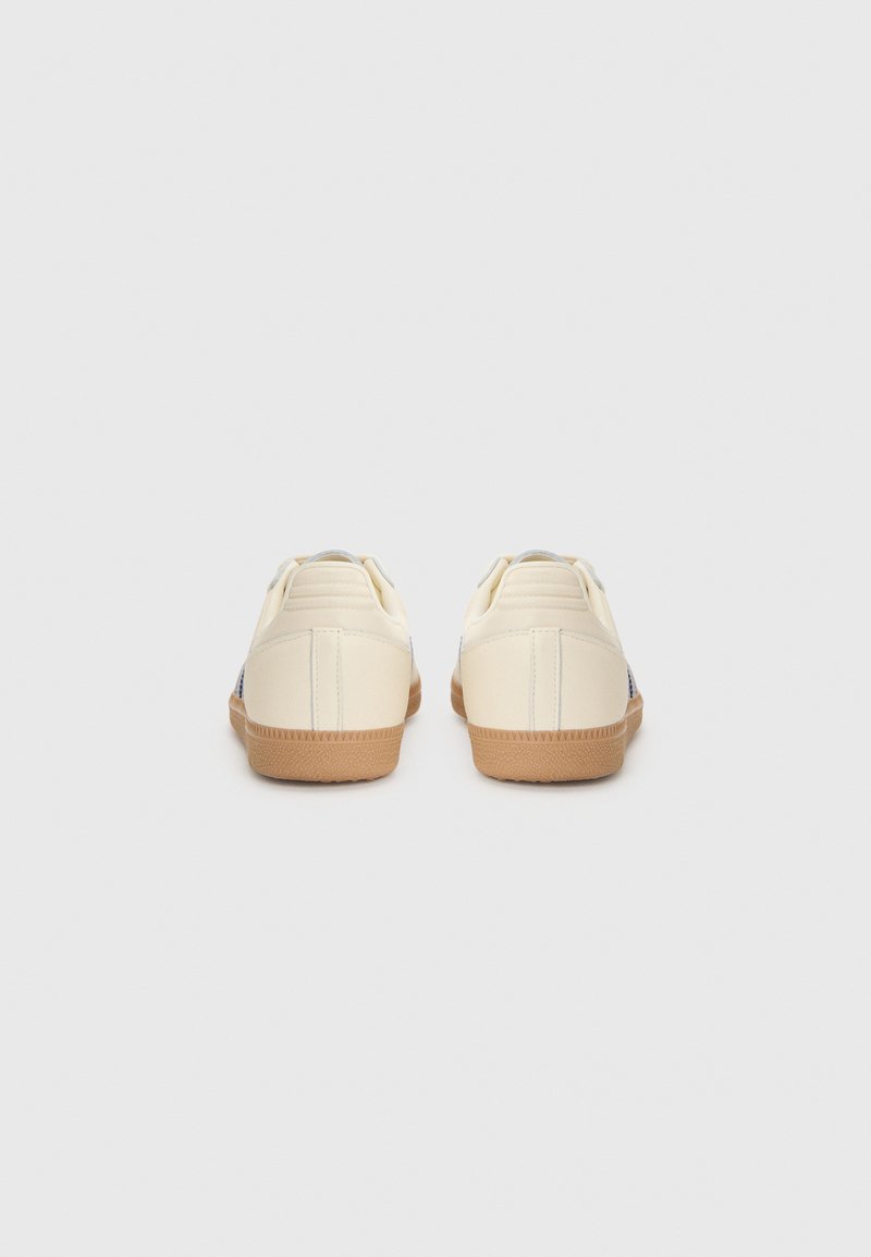 Cremfarbene Sportschuhe mit einer Gummisohle, gepolstertem Schaftrand, hinteren Schlaufen und seitlichen Akzenten. Glatte Lederoberfläche, minimalistisches Design.