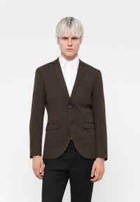 Sacou maro croit, cu închidere cu două butoni, rever �în formă de două laturi și un singur buzunar la piept. Material neted și croială structurată. Purtați peste o cămașă albă.
