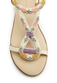 Sandali con perline su una base beige, con accenti geometrici in viola, rosa, giallo e bianco, abbelliti con strass trasparenti.