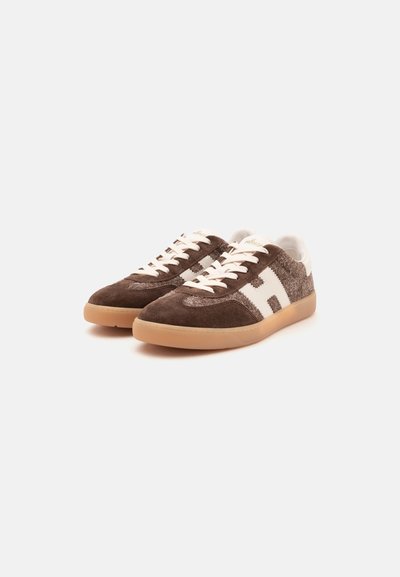Paire de baskets en daim marron et tissu texturé avec lacets blancs, accents blancs sur les côtés et semelles en caoutchouc gomme sur fond blanc.