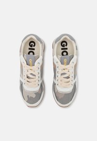 Baskets à motif camouflage avec un tissu en maille gris, beige et blanc, des accents blancs et des lacets beiges. Logo doré sur la languette.