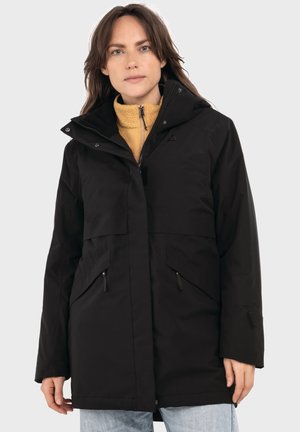 Black waterproof jacket with a hood, two front pockets, and a two-way zipper. Worn over a yellow fleece sweater.