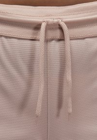 Los pantalones cortos deportivos rosa claro presentan una tela texturizada, cintura elástica con cordón y detalles de costuras finas.