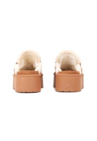 Zoccoli piattaforma marroni con una soffice fodera color crema, retro arrotondato e suola in gomma testurizzata, dotati di un leggero tacco.