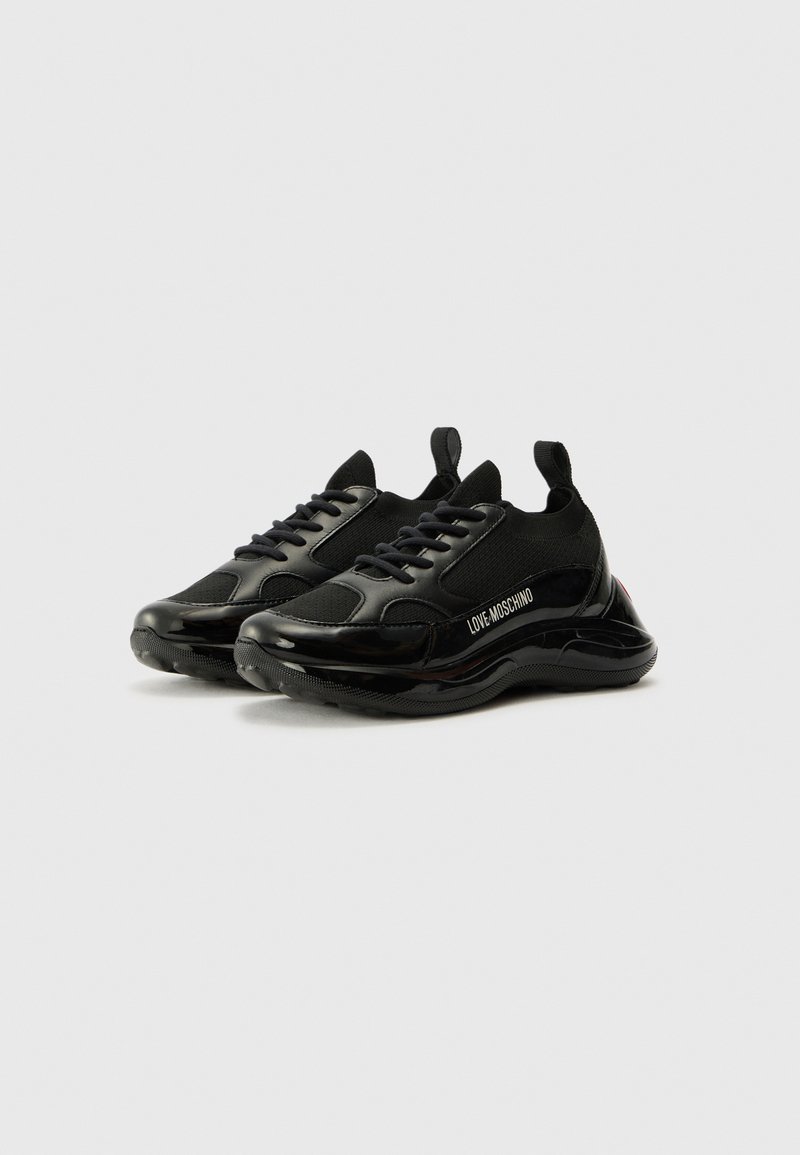 Sneaker sportive nere con una toma in mesh e dettagli lucidi in vernice. Caratterizzate da lacci, linguette e logo laterale.