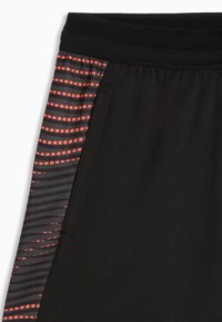 Sorte atletikshorts med en tekstureret, åndbar linning. Sidepanelerne har et geometrisk mønster i orange og grå.