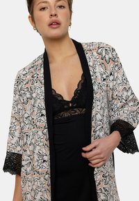 Kimono à motif floral dans des tons de rose pâle et noir, avec une bordure en dentelle aux manches et un col noir contrastant. Design léger et ouvert.