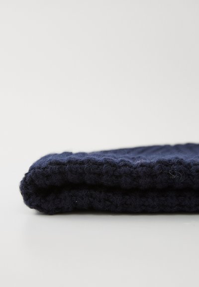 Téxtil din lână tricotată, de culoare bleumarin, pliat. Finisaj texturat, moale, cu fibre vizibile. Formă rectangulară cu un aspect gros și confortabil.
