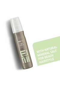 Grå sprayflaska med ett klart lock, märkt "Ocean Spritz", med grön text. Utformad för att förbättra strandfrisyrer med mineralsalt.