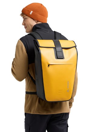 Zaino impermeabile giallo e nero con texture geometrica, chiusura roll-top e tasca frontale con zip. Spallacci regolabili e dettaglio del logo visibile.