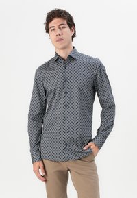 Button-up shirt featuring a navy background with white circular patterns, long sleeves, and a classic collar design.