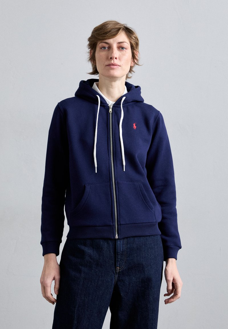 Navy Zip-Hoodie aus Baumwollmischung mit einer Fronttasche, weißen Kordeln und einem kleinen roten Logo auf der Brust.