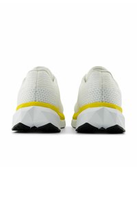 Scarpe sportive bianche con tomaia testurizzata, intersuola gialla e suola nera angolare. Presentano elementi di design moderni e minimalisti.