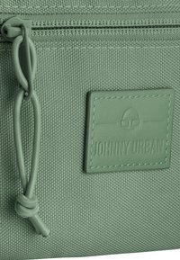 Pochette in tessuto verde con finitura testurizzata, dotata di zip superiore, nodo decorativo e etichetta "JOHNNY URBAN" in rilievo.