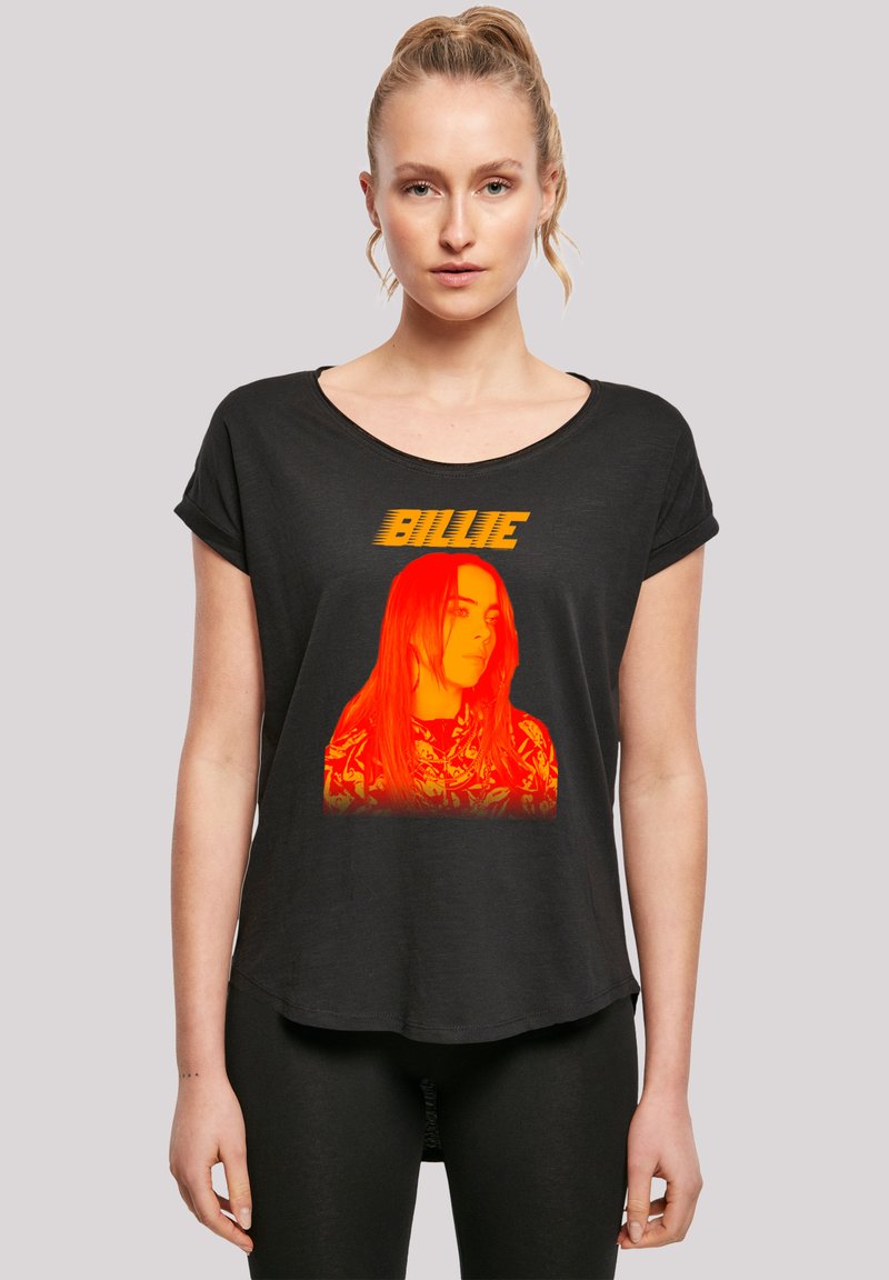 Schwarzes T-Shirt mit lockerer Passform, das ein lebhaftes oranges Grafikbild einer Frau zeigt, mit dem Text "BILLIE" darüber in einer fetten Schriftart.
