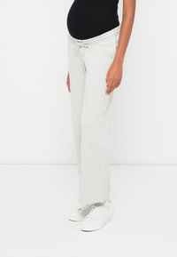 Light grey sweatpants with a drawstring waist, wide legs, and a soft texture, paired with white sneakers.