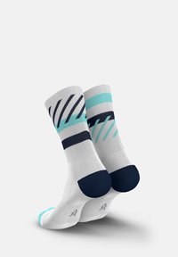 White socks with teal and navy stripes, featuring a smooth texture and contrasting navy heel and toe sections.