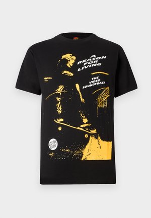 Juodas medvilninis marškinėlis su geltonu grafikų, vaizduojančiu riedlentininką, tekstu: „PRIEŽASTIS GYVENTI“ ir „VIDEO GARSO TAKELIS“. Atsitiktinis sijonas.