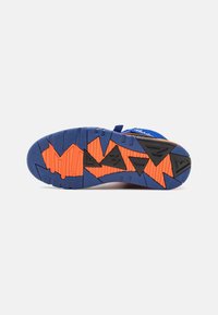 Semelle de chaussure de sport bleue avec un design texturé multicolore, ornée d'accents géométriques orange et noirs pour la traction et la stabilité.