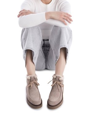 Botas de tobillo de ante marrón con un suave ribete de forro polar color crema y cordones. La suela es texturizada, lo que mejora el agarre y la estabilidad.