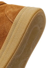 Bruine suède schoen met een textuur rubberen zool. De zool heeft een grip patroon en een naadloze verbinding met de bovenkant van de schoen.