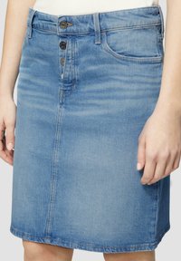 Denim rokje in lichtblauw met een recht model, vijfknopssluiting, voorzakken en zichtbare stikseldetails. Soepele textuur.