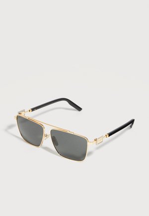 Arany keretes, téglalap alakú napszemüveg sötét lencsékkel és fekete szárral, világos felületen pihenve.